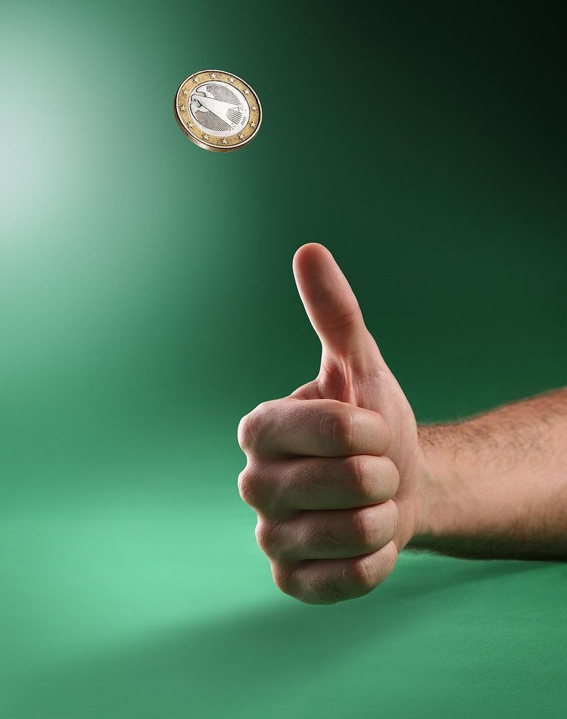 Een duim schiet een munt omhoog tegen een groene achtergrond